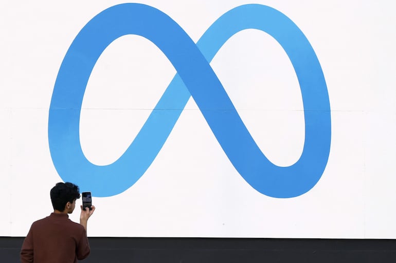 Una persona tomando una fotografía al logo de Meta frente a la sede de la compañía en Menlo Park, California (Estados Unidos). 