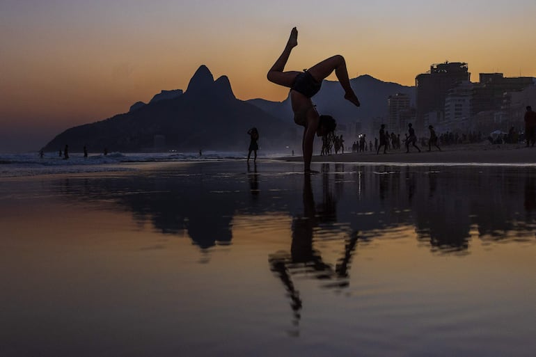 Una joven practicando ejercicios durante la puesta del sol en la playa de Ipanema, Río de Janeiro (Brasil). 