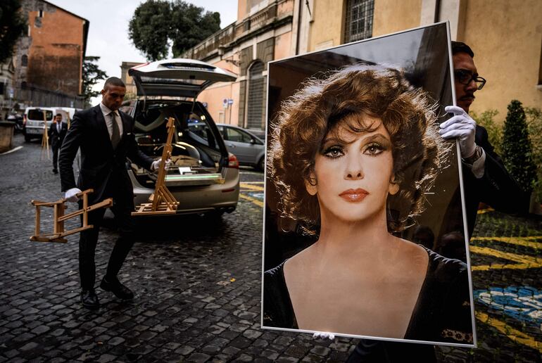 El empleado de una funeraria carga una foto gigante de Gina Lollobrigida, para sus funerales.