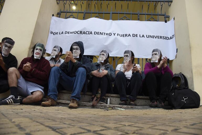 Un grupo de estudiantes portan máscaras con la cara de Narciso Velázquez durante una toma de la Universidad Católica de Asunción.