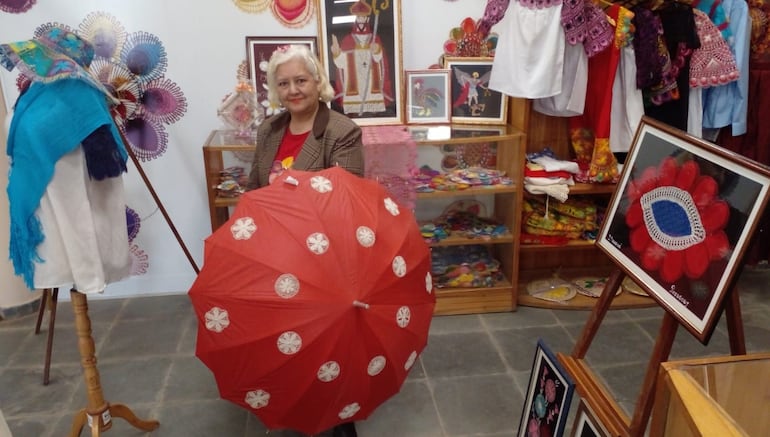 Francisca Acosta exhibe una sombrilla con apliques de ñandutí en el centro de ventas  de la joya artesanal de Itauguá.