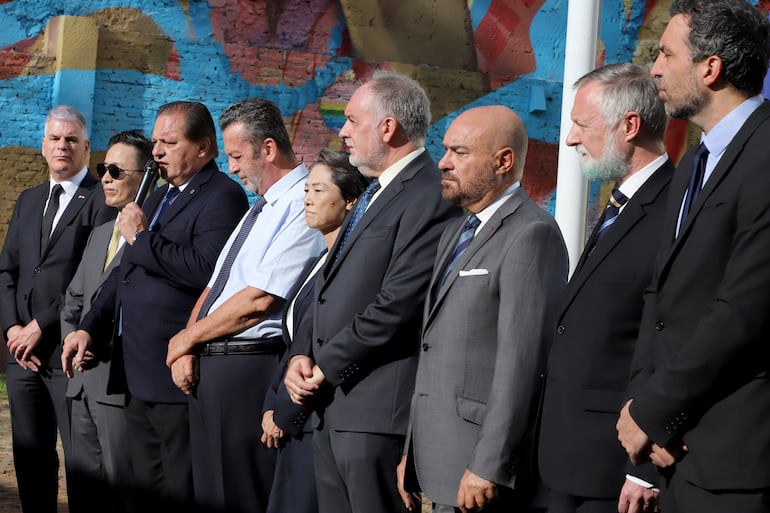 Andrés Trociuk, micrófono en mano, durante el acto de izamiento de la bandera de Ucrania en la sede de la Unión Europea en Paraguay. Lo rodean los embajadores de los Estados Unidos, Marc Ostfield, Corea Chan Sik Yoon; de Italia , Marcello Fondi; de Japón , Nakatani Yoshie, de la Unión Europea, Javier García de Viedma; de Francia, Pierre Christian Soccoja, de Alemania Holger Scherf y del Reino Unido Ramin Navai.