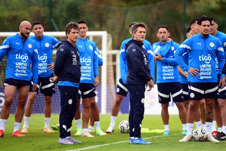 El seleccionador de Paraguay Guillermo Barros Scheloto (c-i) y su hermano Gustavo, asistente técnico, observan un entrenamiento en el centro de entrenamiento CARDE en Ypané (Paraguay). Paraguay se prepara para enfrentar a Perú en la primera fecha de las Eliminatorias Sudamericanas al Mundial de 2026. 
