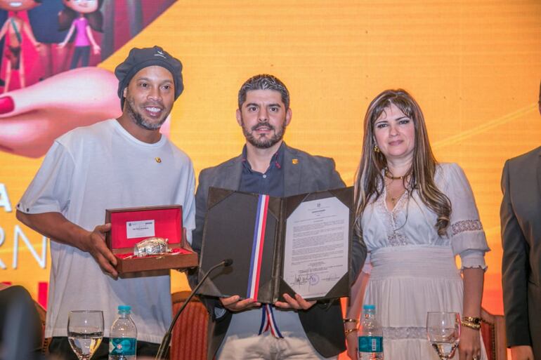 Ronaldinho Gaúcho recibe la distinción de "Visitante Ilustre", el intendente  asunceno Óscar Nenecho Rodríguez, A su lado, la empresaria Dalia López, quien pemanece prófuga.