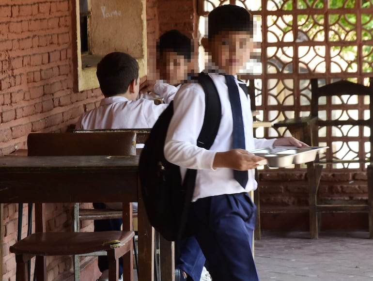 Niños almuerzan en un angosto pasillo en una escuela de Central.