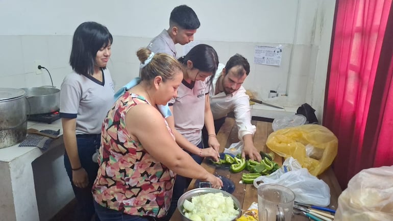 Padres y estudiantes cortan verduras para la olla popular en el centro educativo Juan E. O´Leary de Itá.