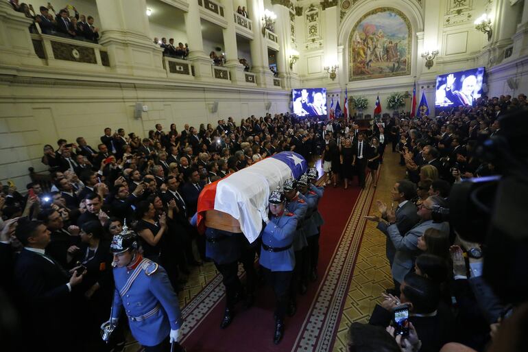 Agentes de la guardia presidencial sostienen el féretro con el cuerpo del expresidente Sebastián Piñera, seguidos por los familiares más cercanos del exmandatario en la antigua sede del Congreso Nacional, en Santiago (Chile).