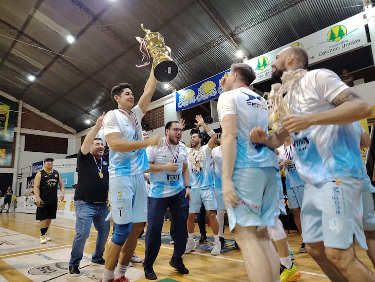 El ala pívot Franco Benítez, uno de los valuartes de las conquistas santas, presenta la copa de campeón a sus compañeros y cuerpo técnico. Foto: Sergio González (corresponsal).