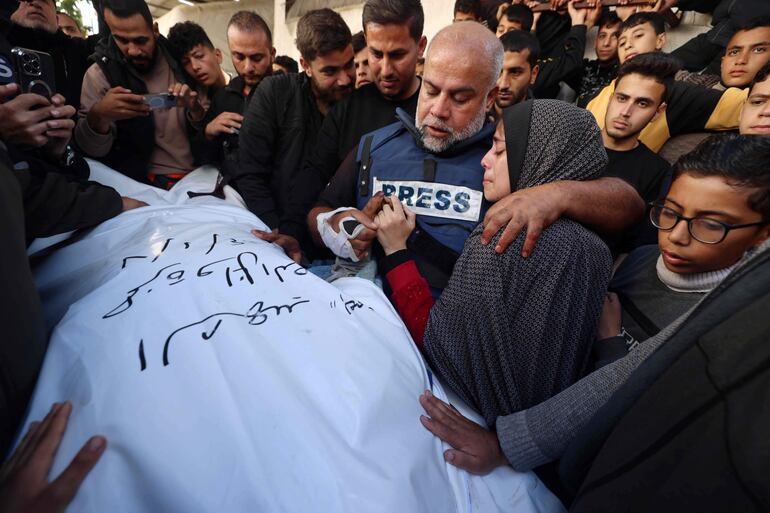 Al Jazeera's bureau chief in Gaza, Wael Al-Dahdouh (C) hugs his daughter as he mourns over the body of his son Hamza Wael Dahdouh, a journalist with the Al Jazeera television network, during his funeral, after he was killed in a reported Israeli air strike in Rafah in the Gaza Strip on January 7, 2024. Dahdouh, who was himself wounded in the arm, lost his wife and two other children in Israeli bombardment in the initial weeks of the war. (Photo by AFP)