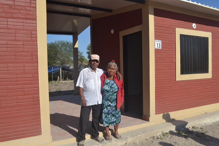 Una pareja de ancianos ishir posando orgullosos frente a su nueva vivienda.