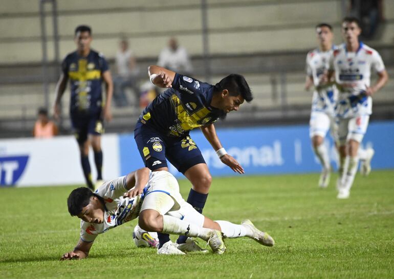 Marcos Riveros, jugador de Sportivo Trinidense, pelea por el balón con Tiago Caballero (blanco), futbolista de Nacional, en un partido por el torneo Clausura 2024 del fútbol paraguayo en el estadio Arsenio Erico, en Asunción, Paraguay.