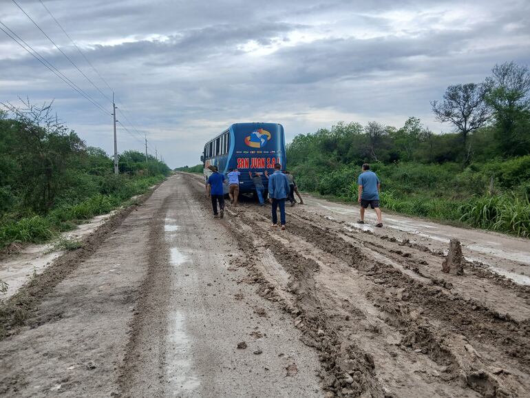 Los pasajeros y choferes en plena tarea de empujar el colectivo en medio del barro.