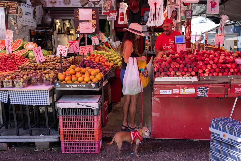 Una mujer compra con su perro en el mercado.