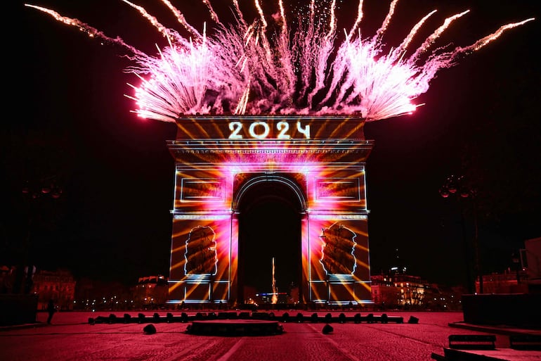 Los fuegos artificiales explotan junto al Arco de Triunfo con “2024” proyectado, en la Avenida de los Campos Elíseos, durante las celebraciones de Año Nuevo en París.