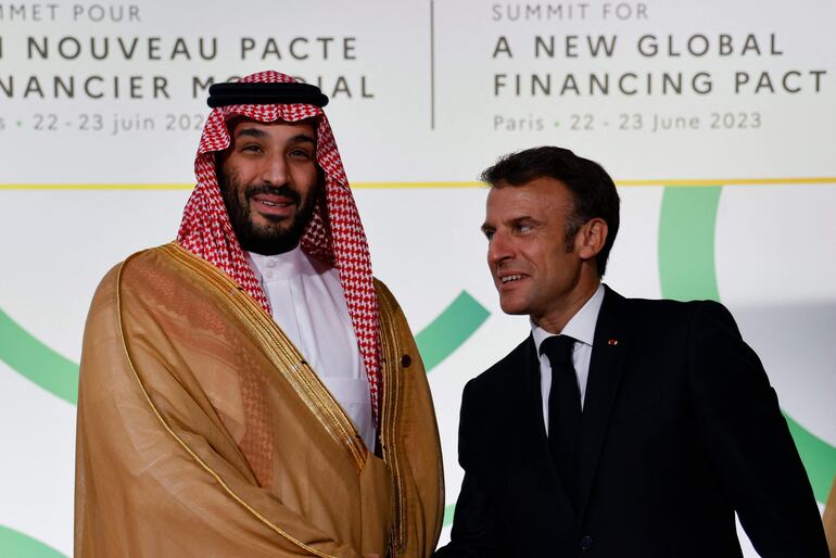 El presidente de Francia, Emmanuel Macron (d) saluda al príncipe heredero saudí, Mohammed bin Salman, en el arranque de la Cumbre de París para un nuevo pacto financiero global.  (AFP)