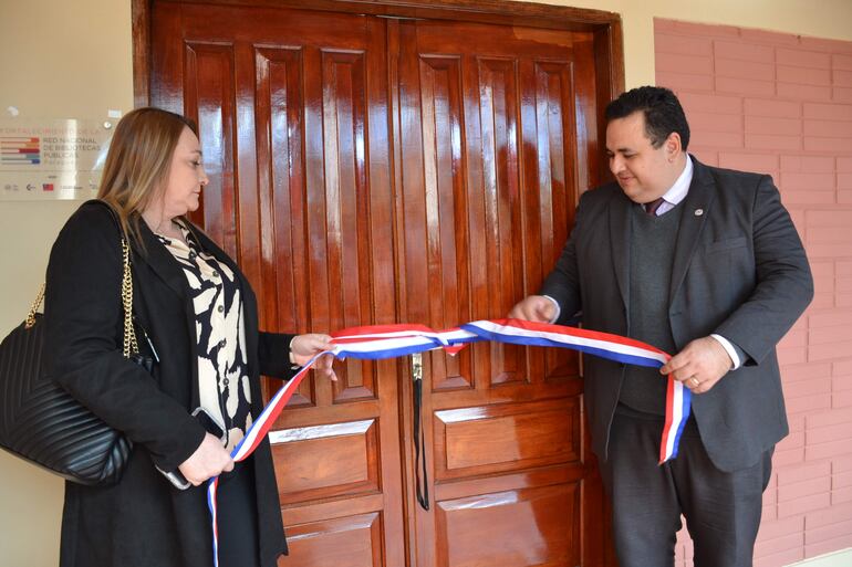 La gobernadora Miriam Mongelos y el coordinador para la implementación de Bibliotecas Públicas, Humberto López, desatando la cinta para dejar habilitada la biblioteca de Caazapá.