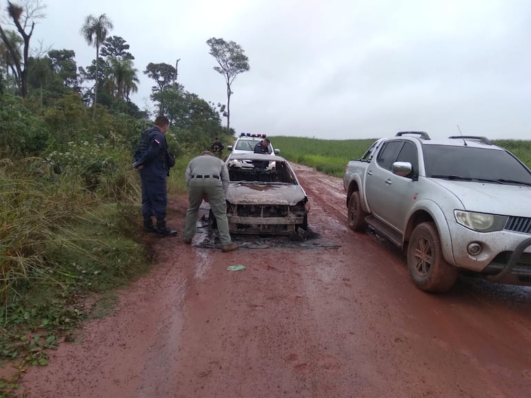 Policías revisan el automóvil que fue quemado con dos cuerpos adentro.