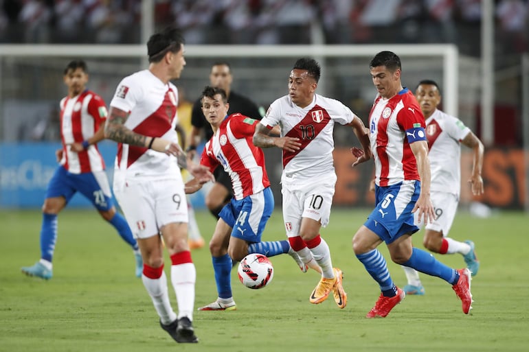 Christian Cueva (c), jugador de Perú, disputa el balón con Fabián Balbuena (d), futbolista de Paraguay, durante un partido de las Eliminatorias Sudamericanas para el Mundial Qatar 2022 en el estadio Nacional, en Lima.
