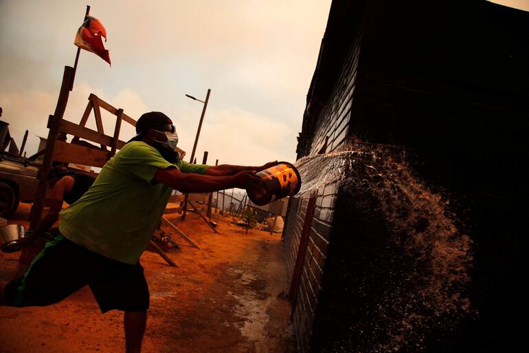 Un hombre intentando combatir el fuego en la zona de un incendio forestal en las colinas de la comuna de Quilpe, región de Valparaíso, Chile.