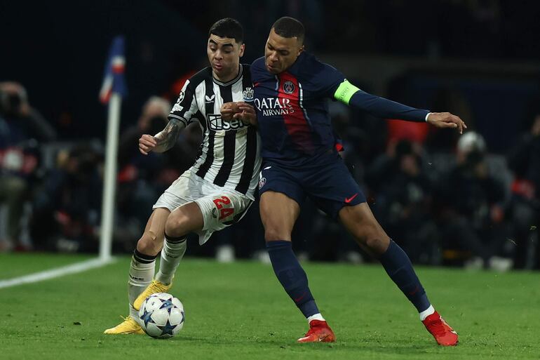 El paraguayo Miguel Almirón (i), futbolista del Newcastle, pelea con Kylian Mbappé, jugador del PSG, en un partido de la Liga de Campeones.