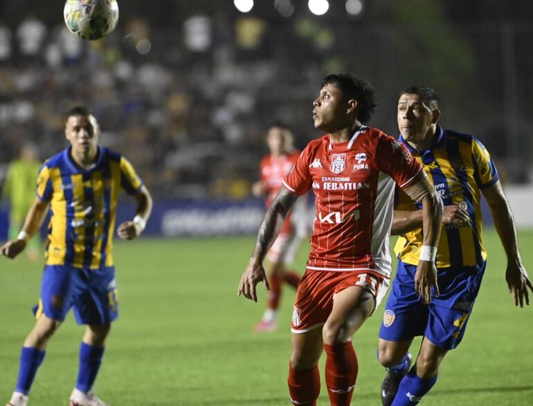 Pedro Delvalle trata de dominar la pelota ante la presencia de dos jugadores de Sportivo Luqueño