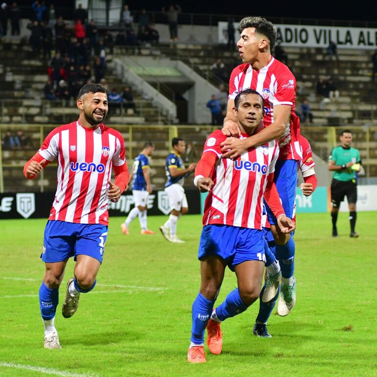 Víctor Maqueda se trepa por el goleador Willian Santander para el festejo del segundo tanto encarnaceno, Alex Garay acompaña la celebración. (Foto: APF)