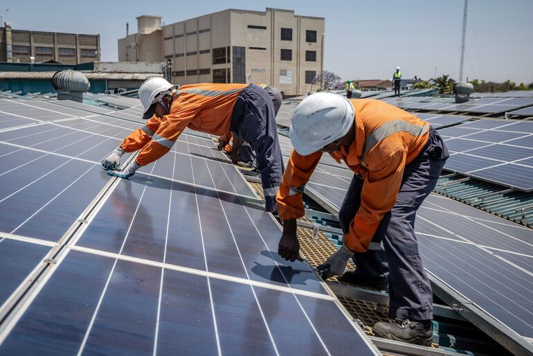 Técnicos instalan paneles solares en una zona industrial de Nairobi, Kenia.