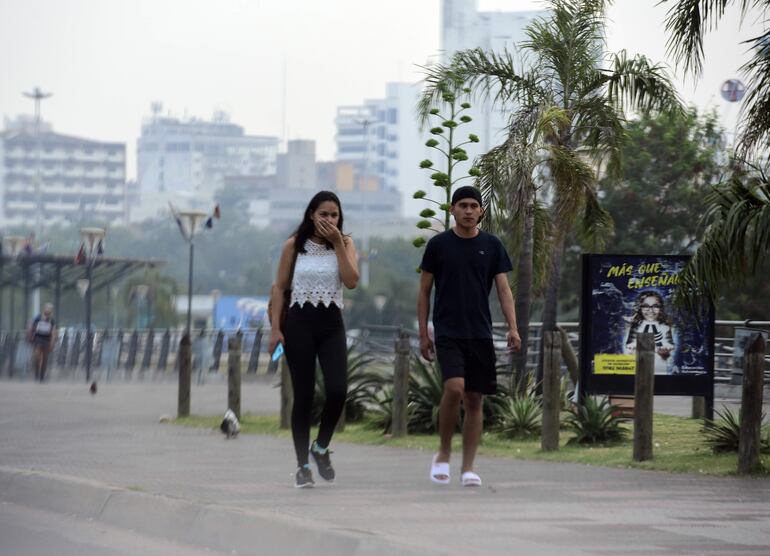 Dos personas caminando en la Costanera de Asunción, en medio de la humareda generada por los incendios forestales.