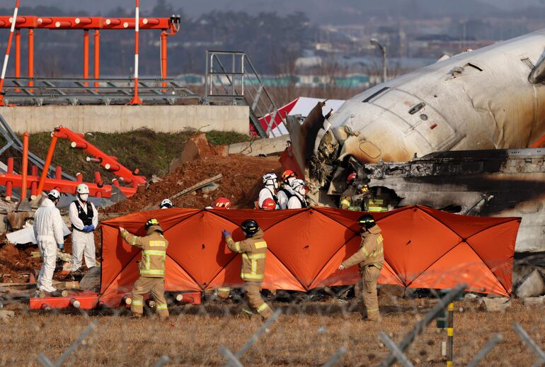 Los bomberos inspeccionan los restos del avión de Jeju Air en el Aeropuerto Internacional de Muan en Muan, a 288 kilómetros al suroeste de Seúl, Corea del Sur, hoy 29 de diciembre de 2024. 