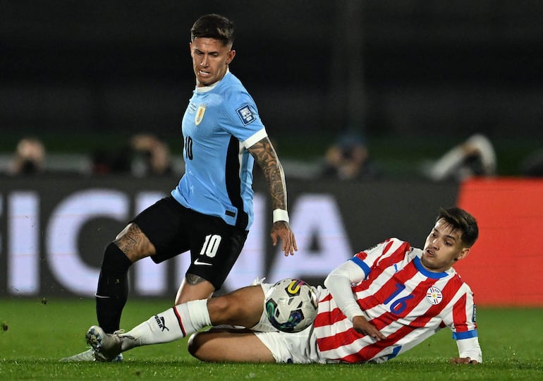 Damián Bobadilla (d), jugador de la selección de Paraguay, pelea por el balón en un partido contra Uruguay por la séptima fecha de las Eliminatorias Sudamericanas en el estadio Centenario, en Montevideo.