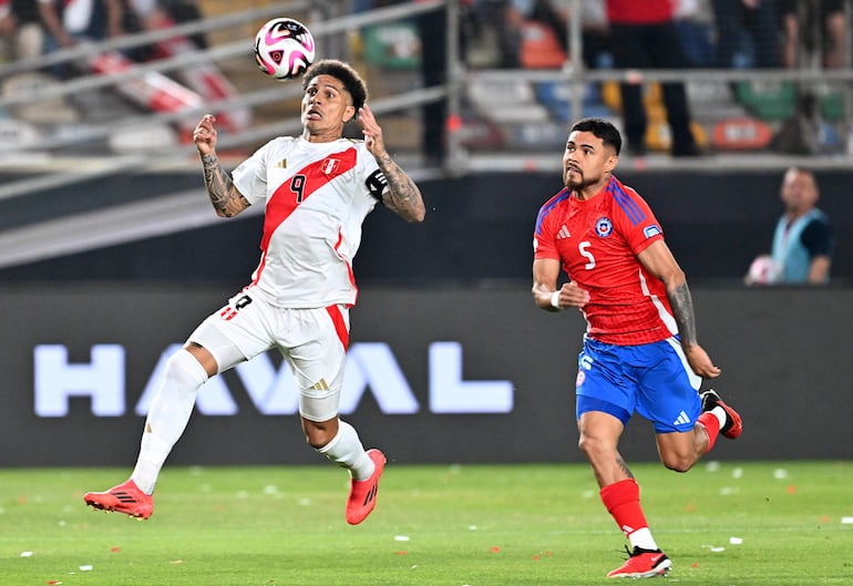 Paolo Guerrero, capitán de Perú, salta en procura del balón ante la marca del chileno Felipe Loyola.