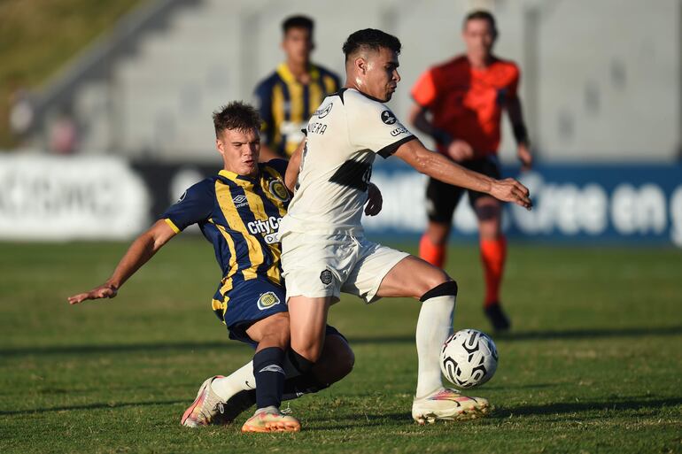 Mateo Serra (i) de Rosario disputa un balón con el atacante franjeado, Freddy Noguera de Olimpia en el partido de la Copa Libertadores Sub-20, en el estadio Alberto Suppici en Colonia del Sacramento (Uruguay).