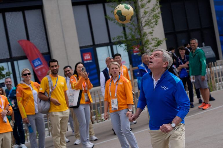 El presidente del Comité Olímpico Internacional (COI), Thomas Bach, controla un balón mientras recorre la villa de los atletas en Saint-Denis, cerca de París, el 22 de julio de 2024, antes de los Juegos Olímpicos de París 2024.