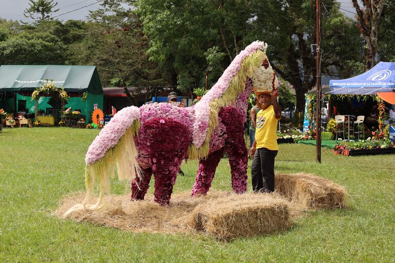 Un hombre toca la figura de un caballo elaborado con flores en la octava edición de la "Parada de las Flores".