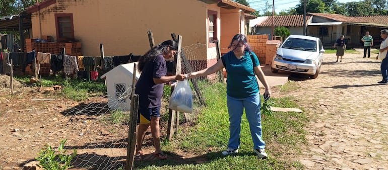 Una voluntaria del Santuario Virgen del Rosario entrega una bolsa de víveres a una familia de Luque.