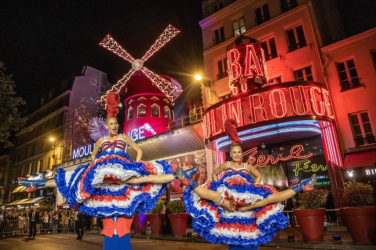 Bailarinas del Moulin Rouge bailan can can frente al famoso local de París.