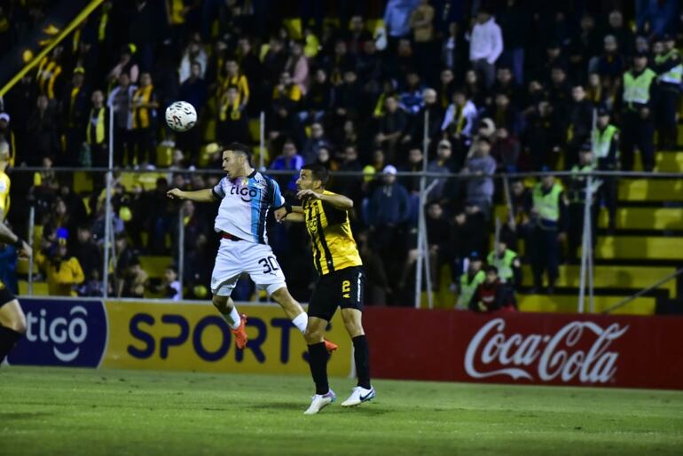 Enso González, de Libertad, disputa el balón con Raúl Cáceres, de Guaraní, en el estadio Rogelio Silvino Livieres.