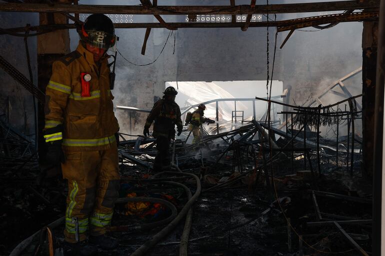 Bomberos voluntarios controlan un incendio de gran magnitud en un depósito de ropa deportiva.