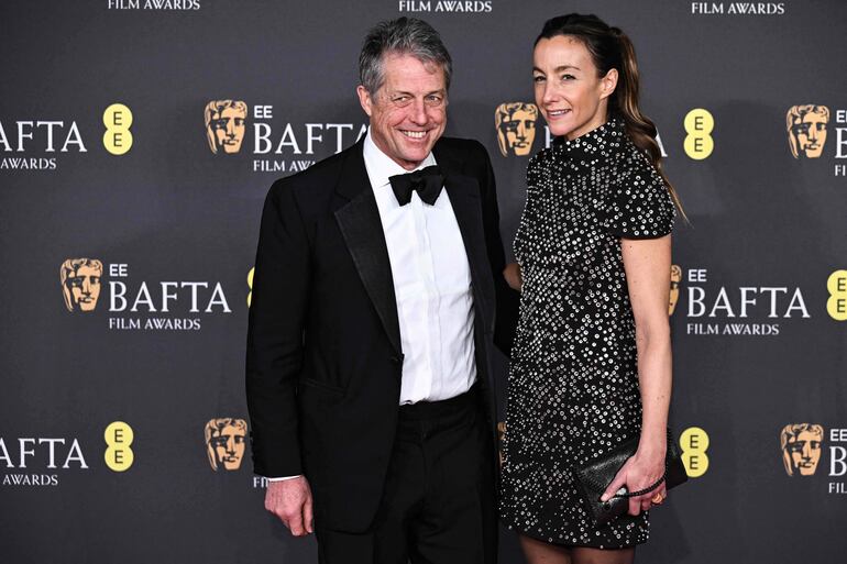 El actor británico Hugh Grant y la productora de televisión sueca Anna Elisabet Eberstein posan en la alfombra roja a su llegada a los premios BAFTA de cine de la Academia Británica en el Royal Festival Hall, Southbank Centre, en Londres. (Ben STANSALL / AFP)