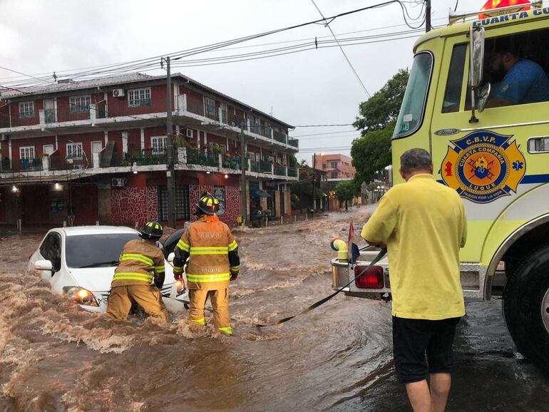 bomberos voluntarios rescatando moviendo un vehículo blanco en el raudal