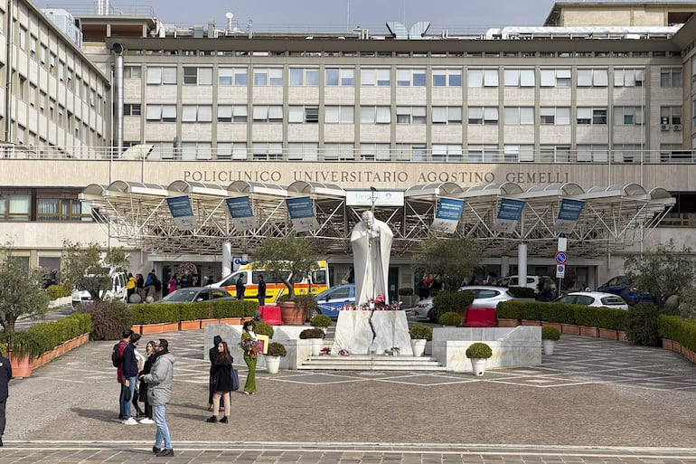 Velas y flores a los pies de la escultura de Juan Pablo II a las puertas del Hospital Gemelli de Roma donde permanece ingresado el papa Francisco.