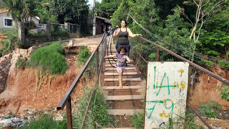 El precario puente que utilizan los vecinos del barrio Mbocayaty de San Antonio está a punto de caer, con cada lluvia las cabeceras erosionan, y la calle termina por el barranco.