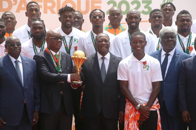 Abidjan (Cote D''ivoire), 13/02/2024.- President of the Ivorian soccer Federation Yacine Idriss Diallo (C-L) and President of Ivory Coast Alassane Ouattara (C-R) hold the Africa Cup of Nations trophy as they pose for a photo with the Ivory Coast soccer team during a reception at the Presidential Palace in Abidjan, Ivory Coast, 13 February 2024. Ivory Coast on 11 February won the CAF 2023 Africa Cup of Nations final against Nigeria. (Costa de Marfil) EFE/EPA/LEGNAN KOULA
