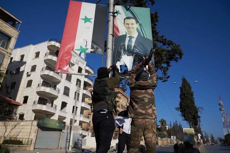 Aleppo (Syrian Arab Republic), 30/11/2024.- - Combatientes de la oposición siria rompen un retrato del presidente sirio Bashar al-Assad en el centro de Alepo, Siria, el 30 de noviembre de 2024. Las fuerzas de oposición siria han tomado un control significativo de Alepo, una ciudad importante y antiguo centro económico de Siria, después de intensos combates con las fuerzas gubernamentales. La ofensiva desencadenó ataques rusos contra Alepo el 30 de noviembre de 2024, los primeros desde 2016, y el ejército sirio retiró sus tropas de la ciudad. El ataque fue liderado por el grupo militante islamista Hayat Tahrir al-Sham (HTS). (Rusia, Siria) EFE/EPA/KARAM AL-MASRI