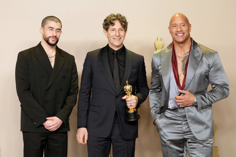 Los Angeles, 10/03/2024.- Jonathan Glazer (al centro), ganador del Oscar a la Mejor Película extranjera por 'Zona de Interés', Bad Bunny (izq.) y Dwayne Johnson (der.) durante la 96 Ceremonia Anual de los premios de la Academia en el Dolby Theatre de Hollywood. EFE/EPA/ALLISON DINNER