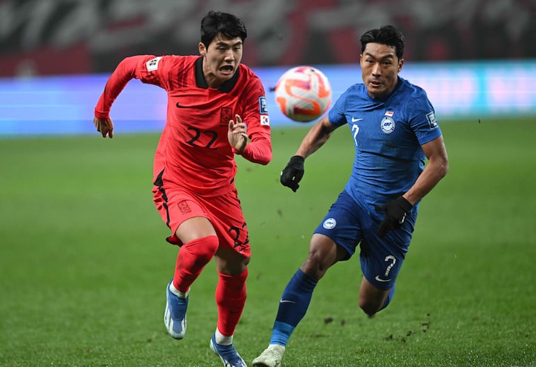 Seol Young-woo (i), zaguero de Corea del Surl, disputa el balón con Song Ui-Young, mediocampista de Singapur, durante el partido que jugaron ayer.