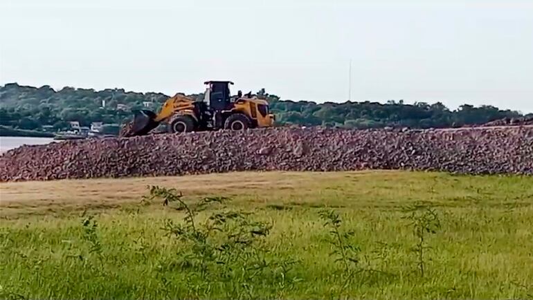 Un tractor se encargada de trasladar y compactar la piedra del muro que avanza hacia el río Paraguay. Los trabajos se hacen pese a resolución municipal.