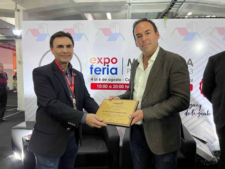 El titular del MUVH, Dr. Carlos Pereira, recibiendo la placa de distinción de Caprivi, por parte de su titular, Blas Reguera Riquelme, en el marco de la 2° Expo Mi Vivienda, en el Centro de Convenciones Mariscal.