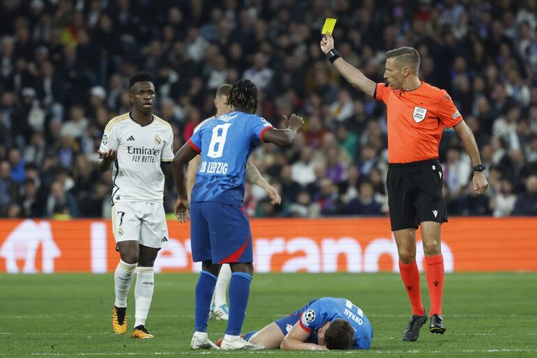 MADRID, 06/03/2024.- El árbitro Davide Massa (d) muestra la tarjeta amarilla a Vinicius Junior (i), del Real Madrid, durante el partido de vuelta de los octavos de final de la Liga de Campeones que Real Madrid y RB Leipzig disputan este miércoles en el estadio Santiago Bernabéu. EFE/Juanjo Martín
