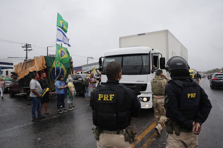 Fotografía de la manifestación: miembros de la policía custodian a grupos de camioneros que bloquean carreteras en Río de Janeiro (Brasil).
